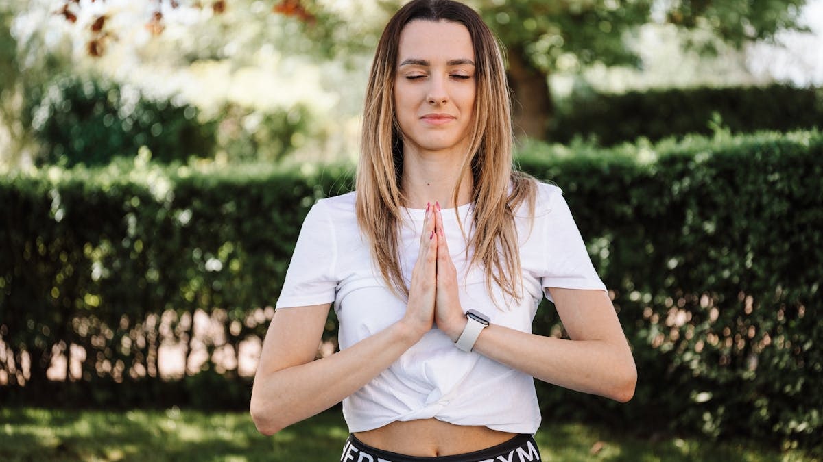 A serene moment of a woman practicing yoga with namaste pose outdoors, embracing mindfulness.